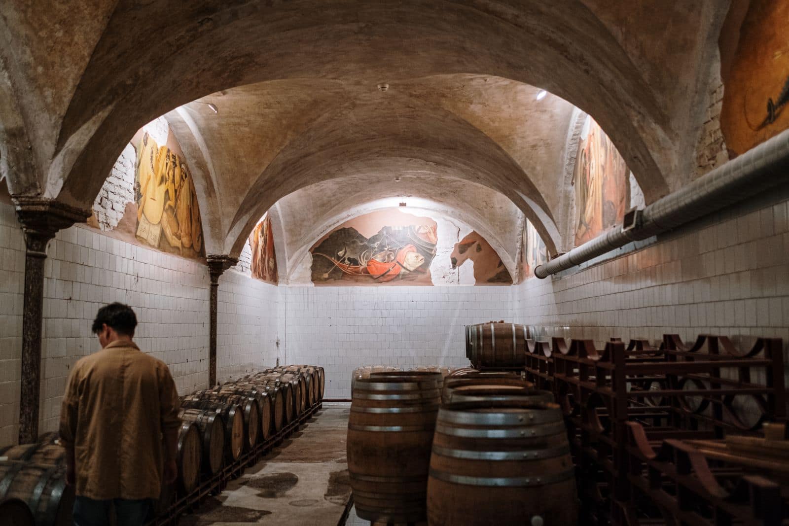Wine barrels in an arched cellar. Photo by cottonbro studio via Pexels.