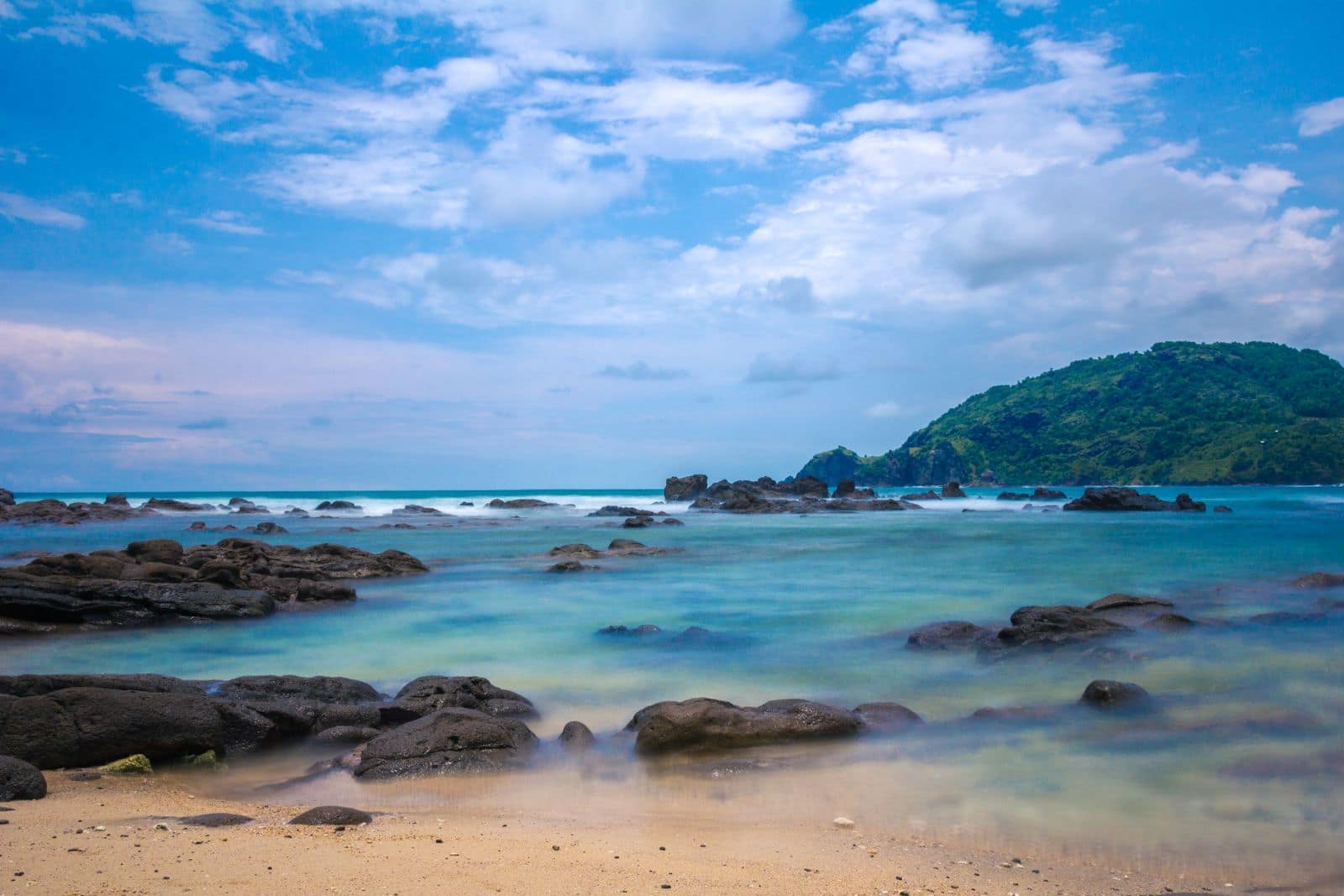 A quiet rocky cove with clear turquoise water and a green headland. Photo via Pexels (photo 188014).