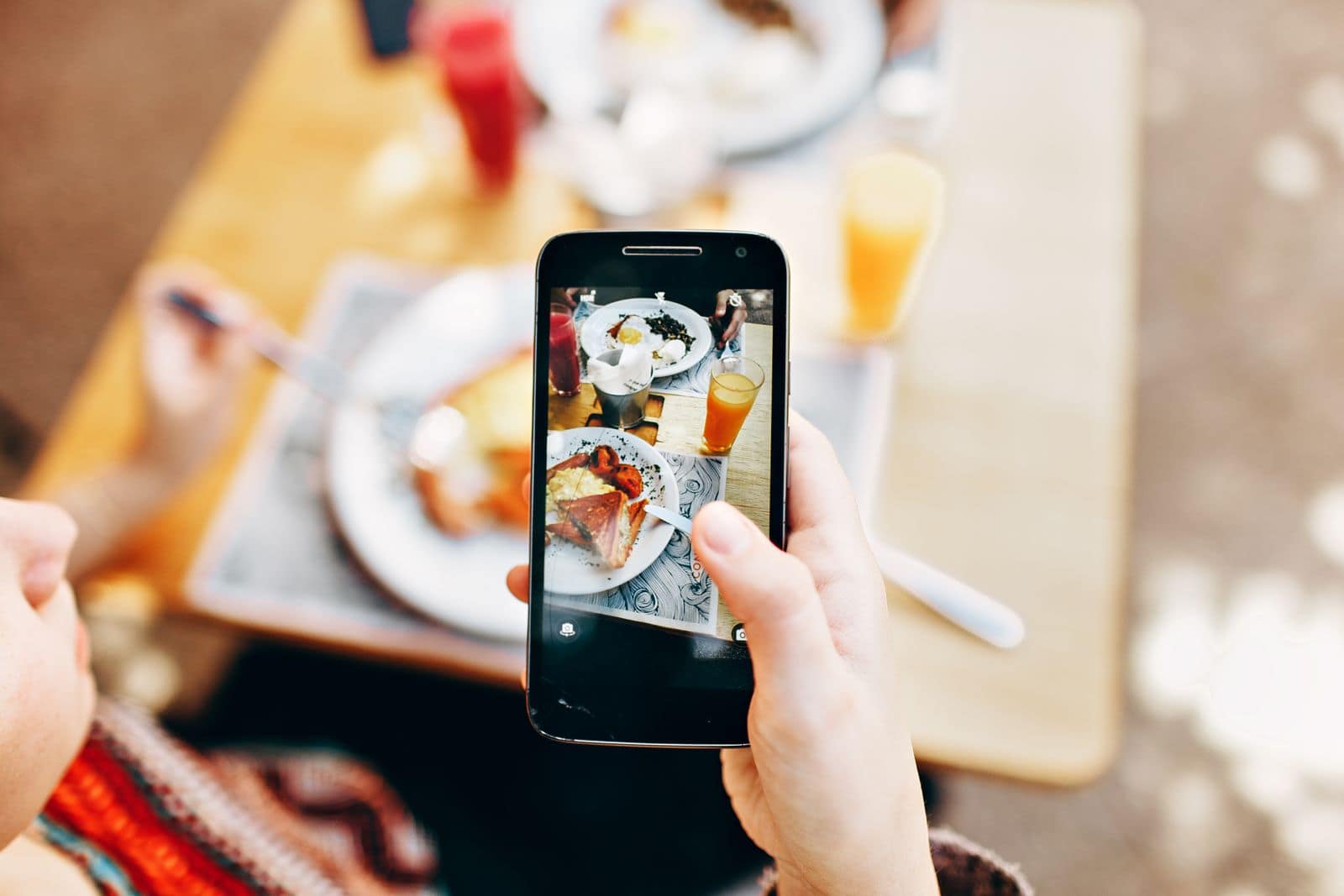 Photographing a served meal on a phone. Photo by (Pexels) via Pexels.