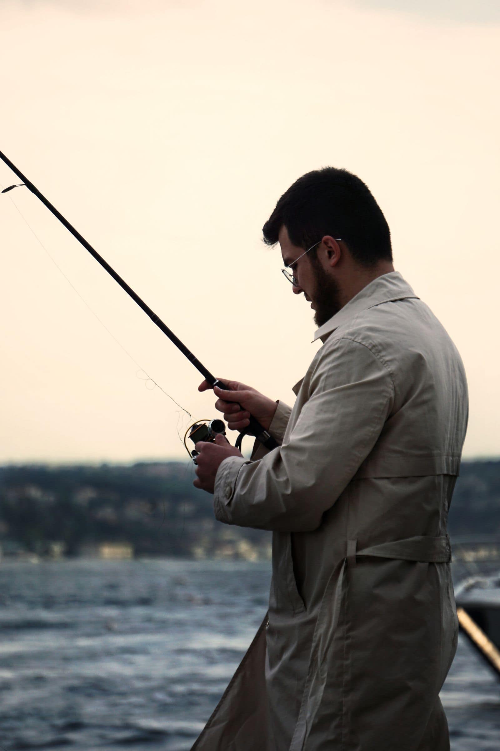 A man fishing from a harbour wall at sunset. Photo by (Pexels) via Pexels.